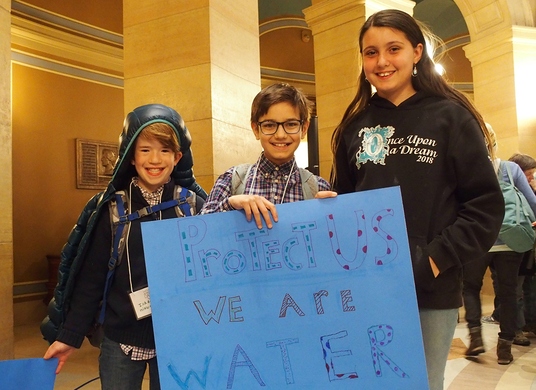 Children with a sign that reads "Protect Us We are Water"