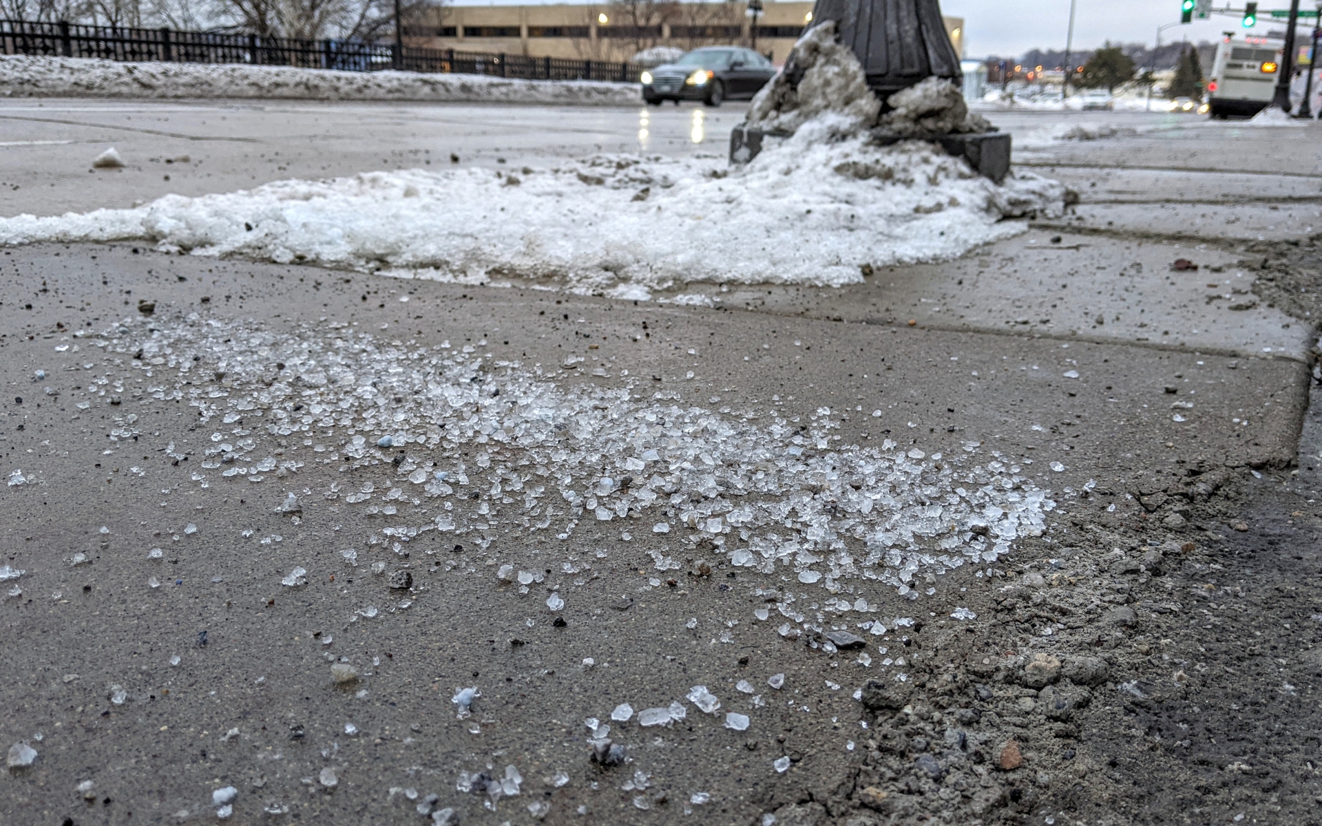 A pile of deicing salt piled along a sidewalk in winter. 