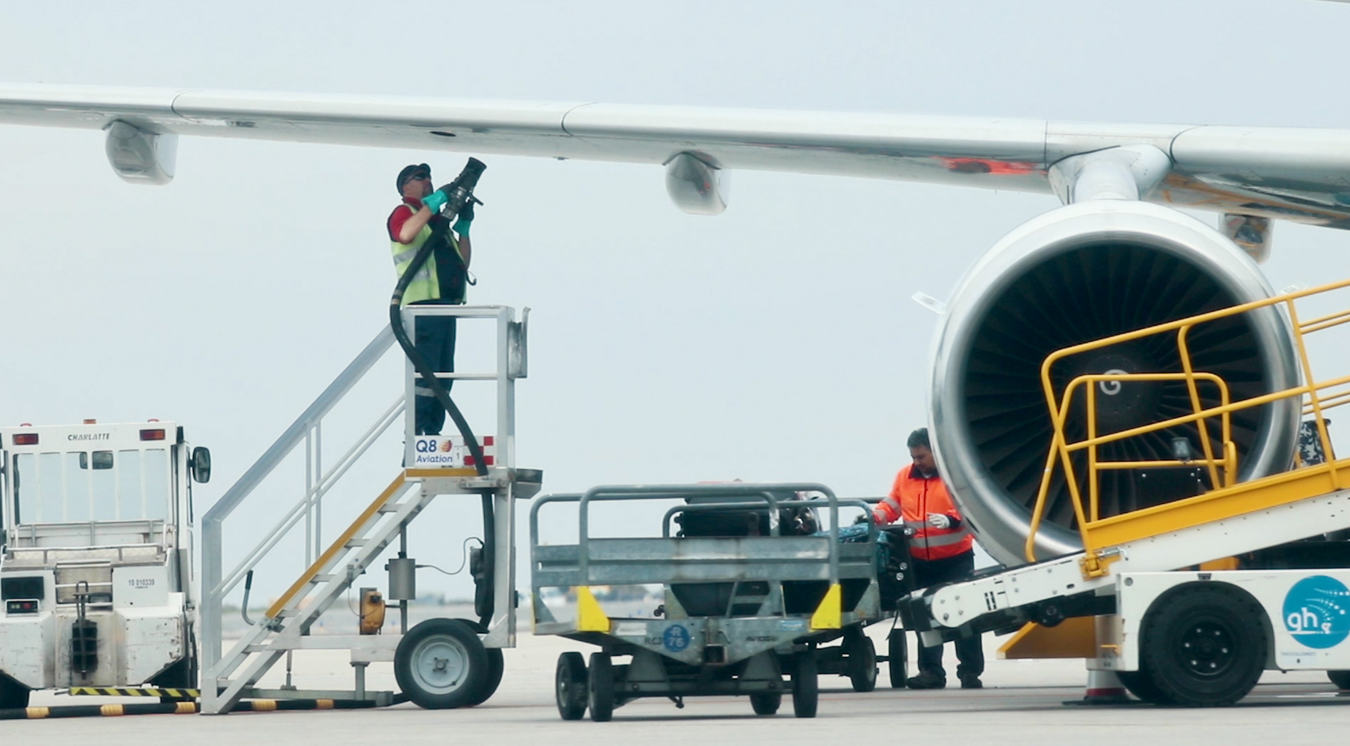 A worker refueling an airplane while standing beneath its wing.