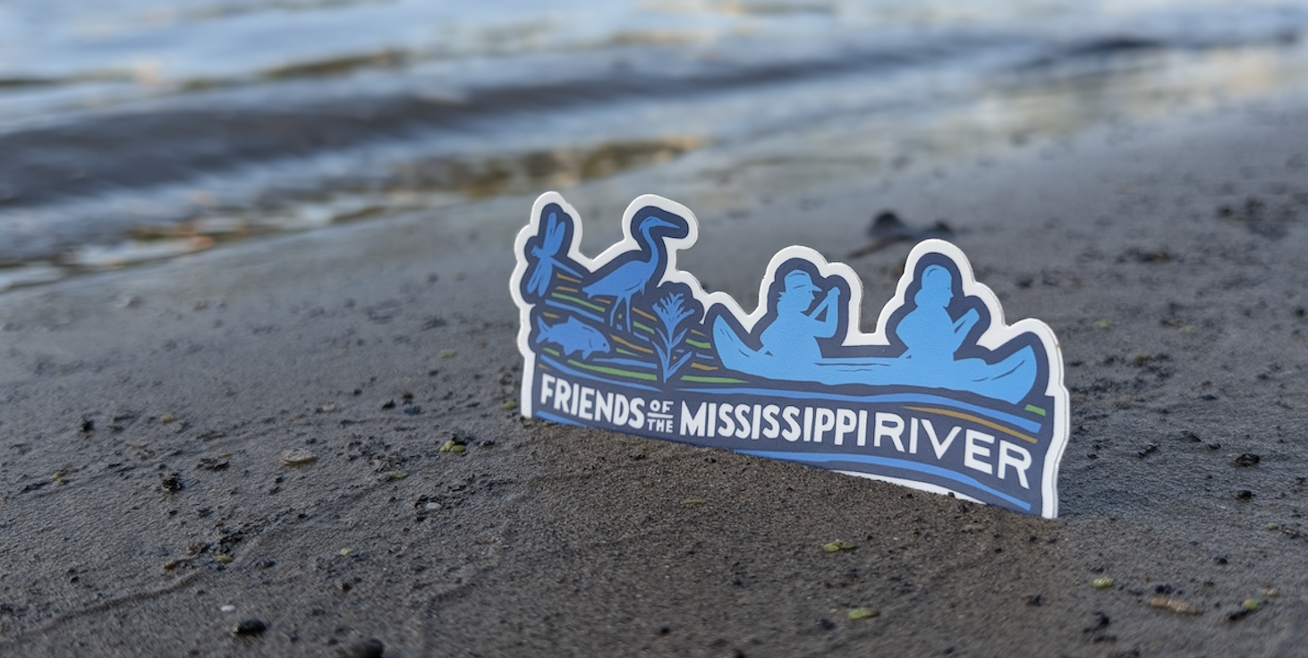 An FMR sticker in the sand on the banks of the river.