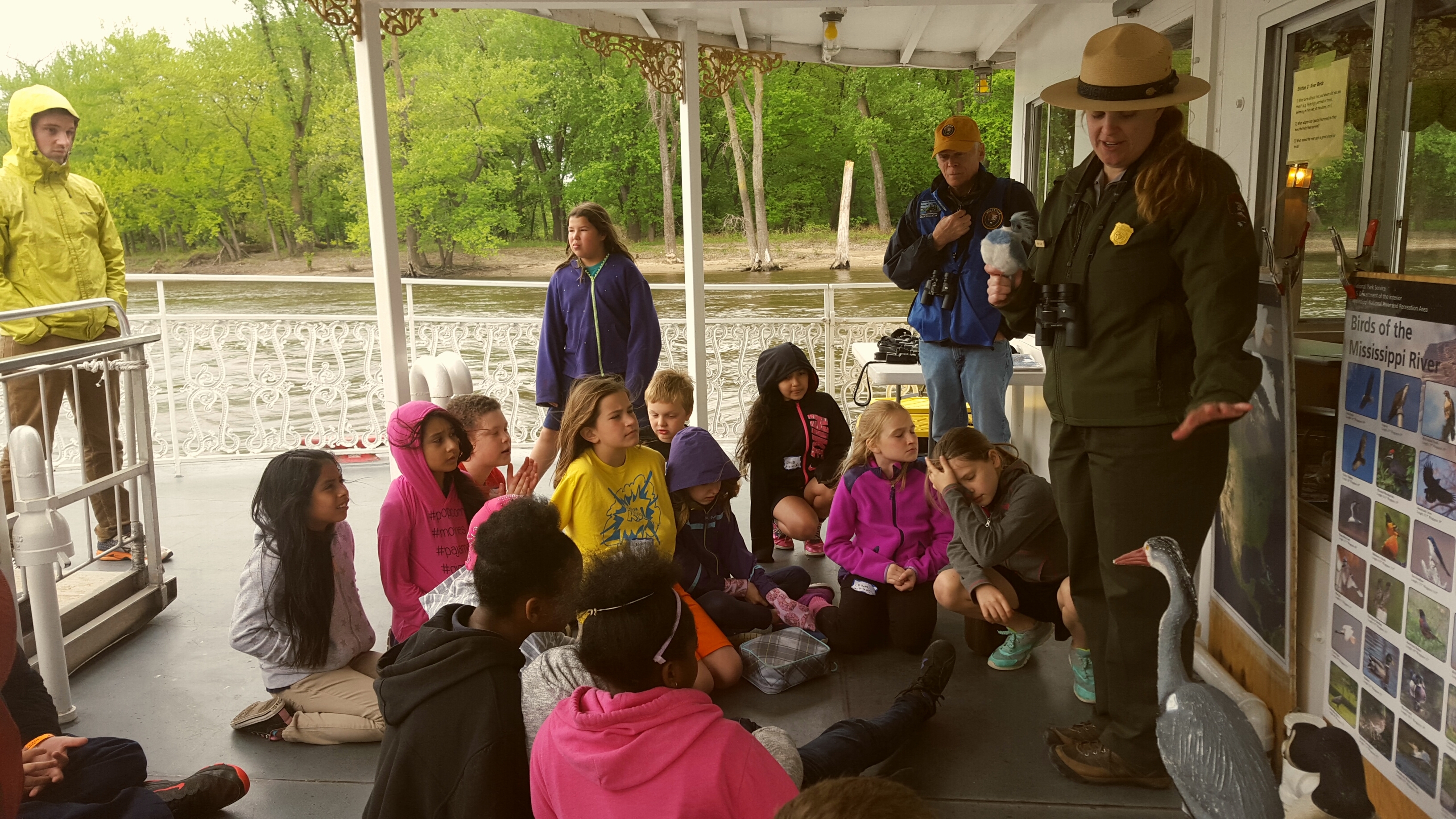 Students gather around a ranger on a boat on the Mississippi River