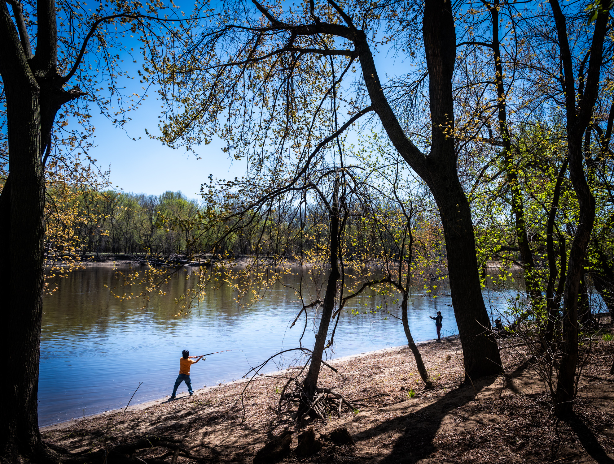 Two people fish by the river