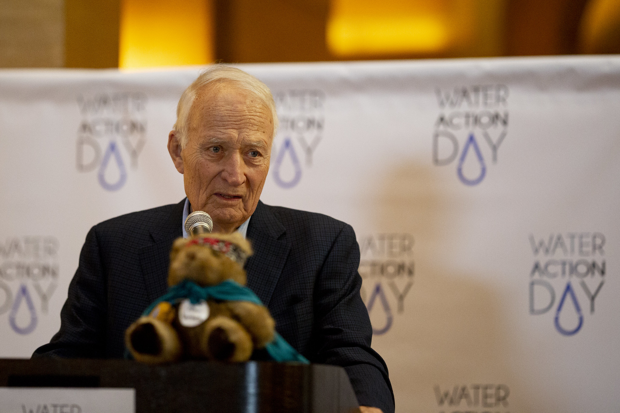 David Durenberger, in a suit and speaking behind a microphone at Water Action Day at the Minnesota Capitol rotunda in 2018. 