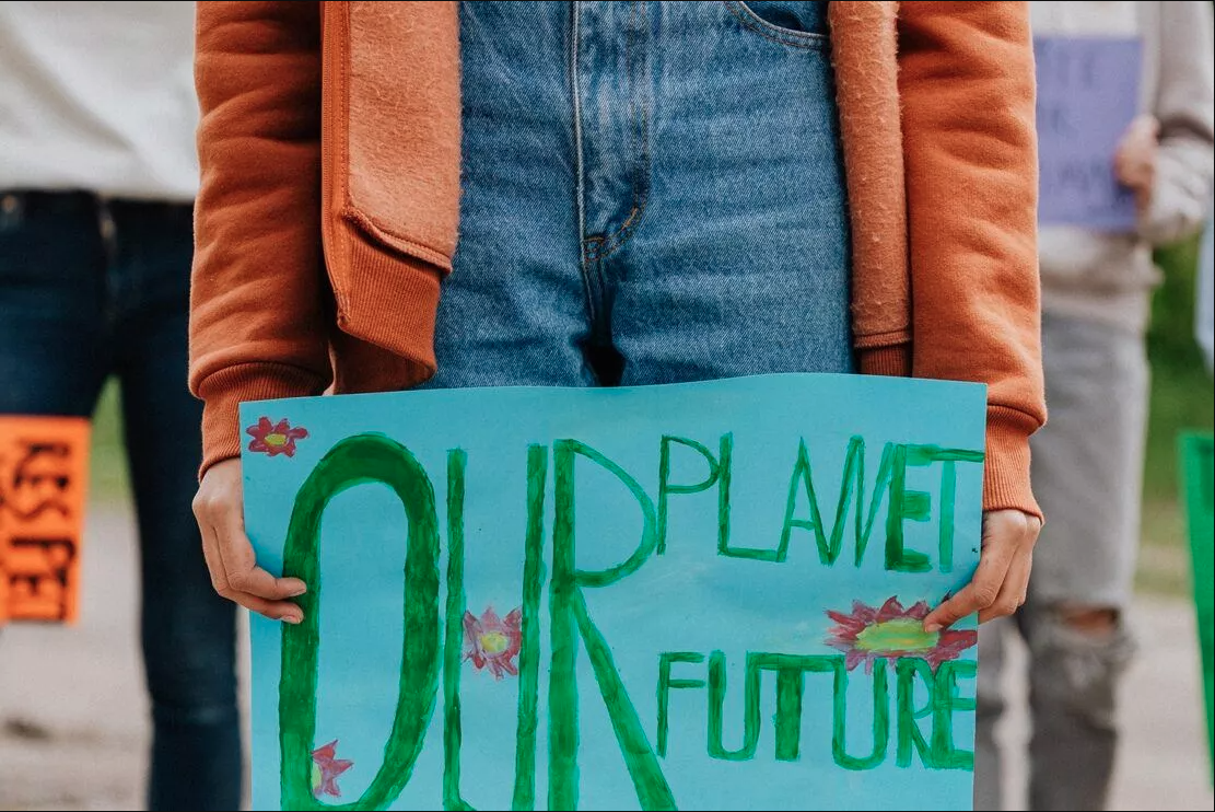 Young person holding "Our planet, our future" sign.