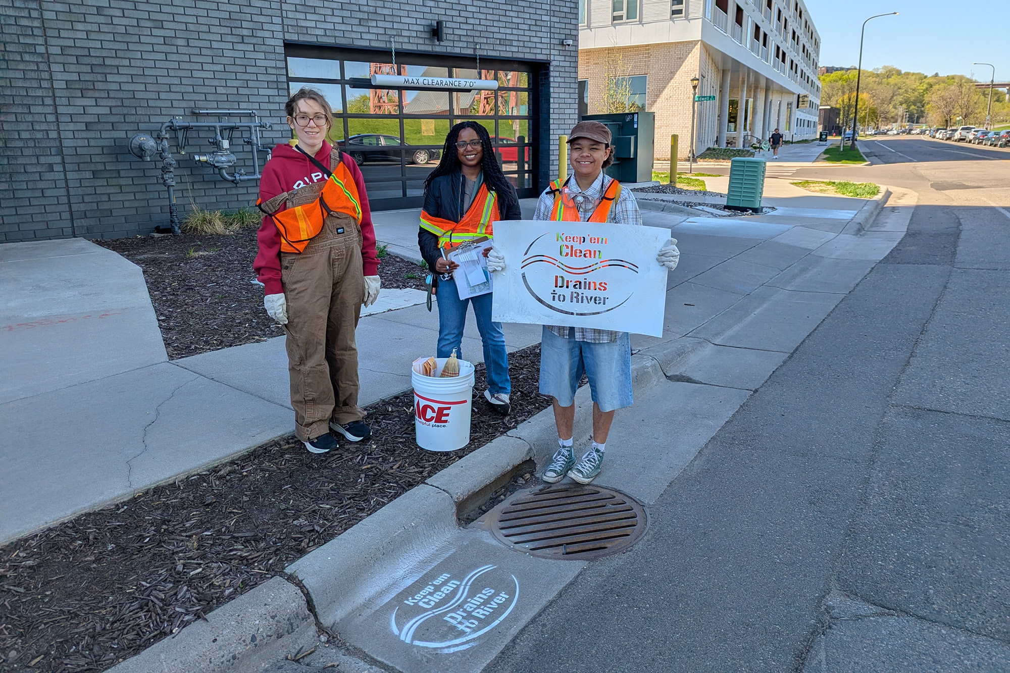 ESI council members hold up storm drain stencil by storm drain