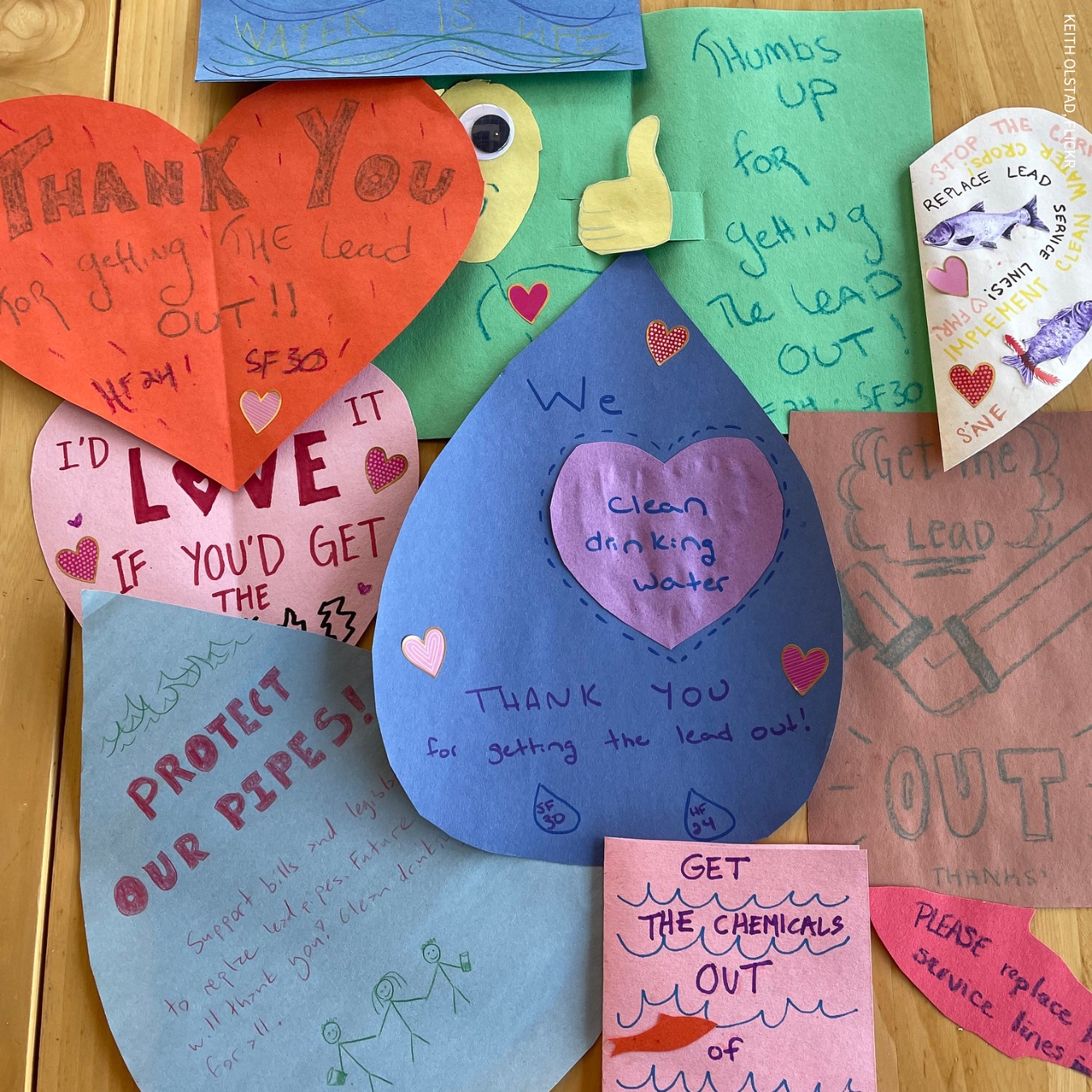A collection of handmade Valentine's Day cards on colored construction paper. All have messages written in marker about replacing lead service lines.