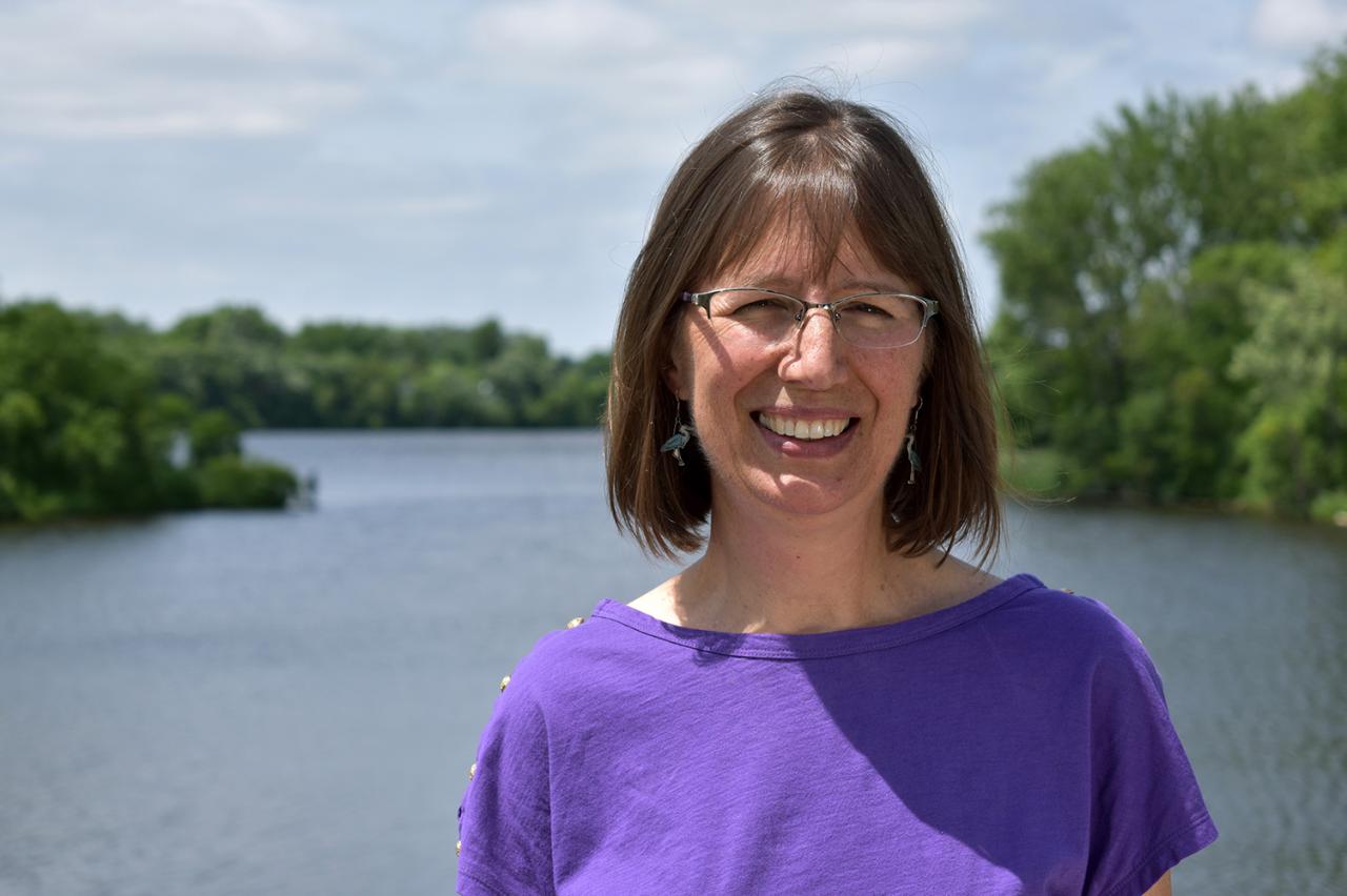 Karen Schik smiling for the camera while standing in front of the Mississippi River.