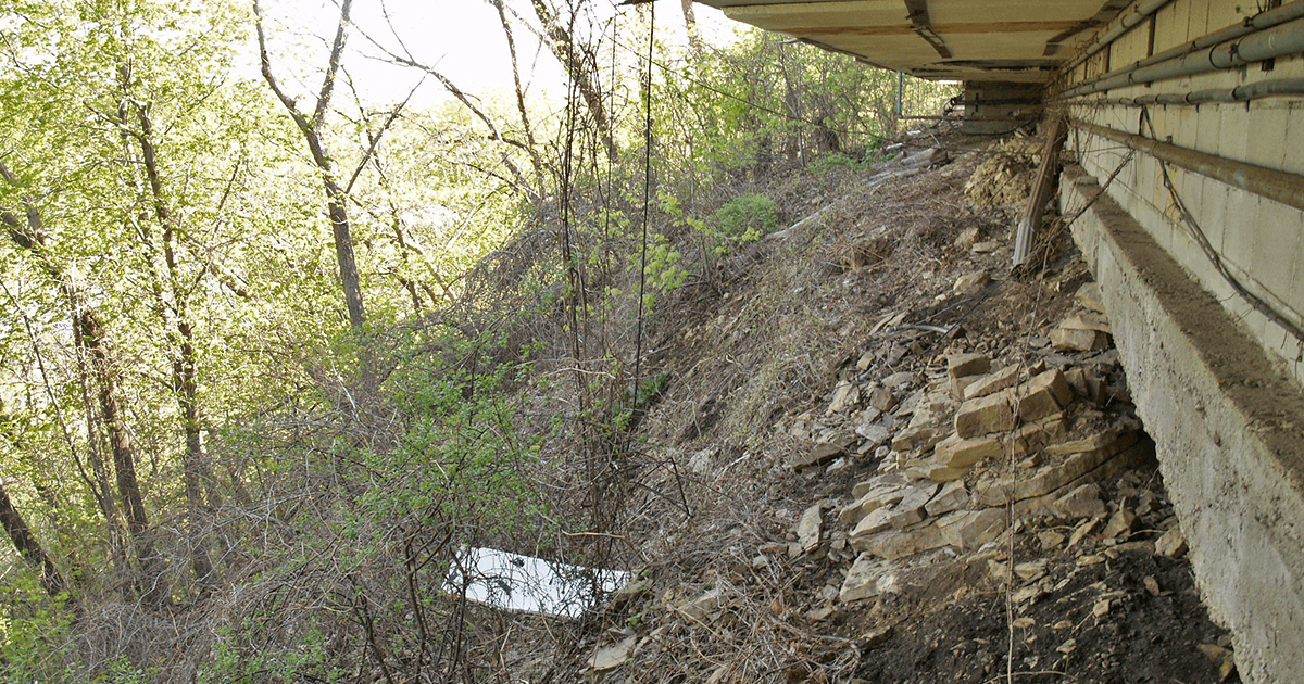 Building foundation at edge of bluff with exposed dirt 