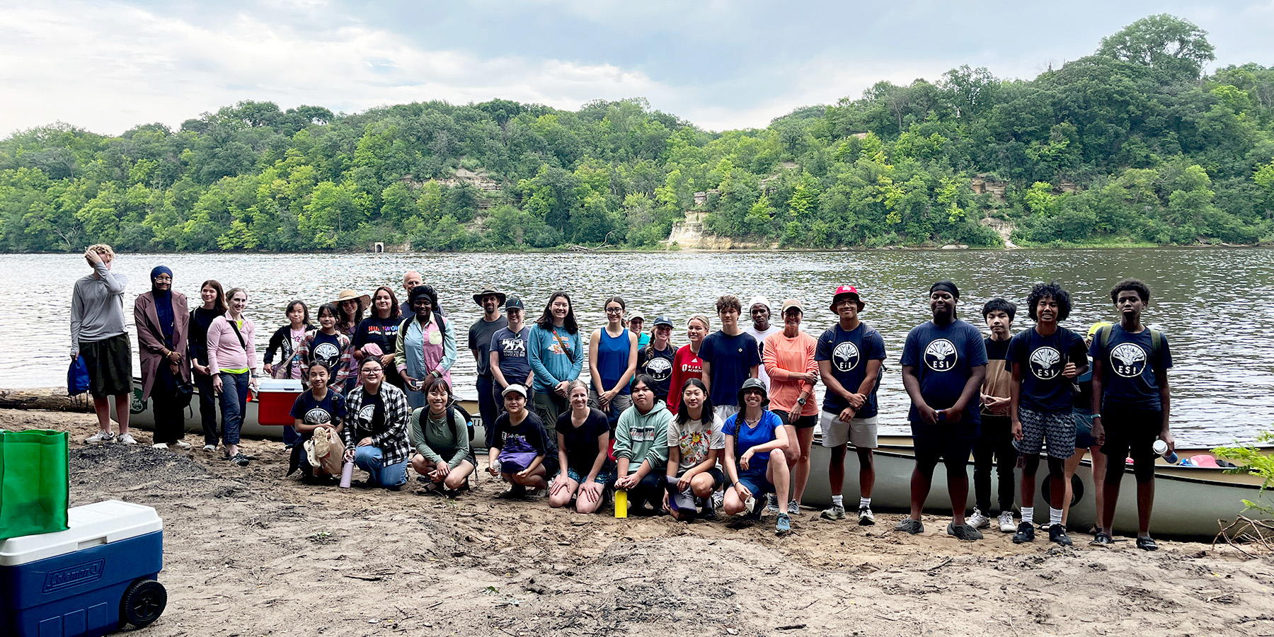 ESI fellows and guests stand on the shoreline in the gorge with canoes