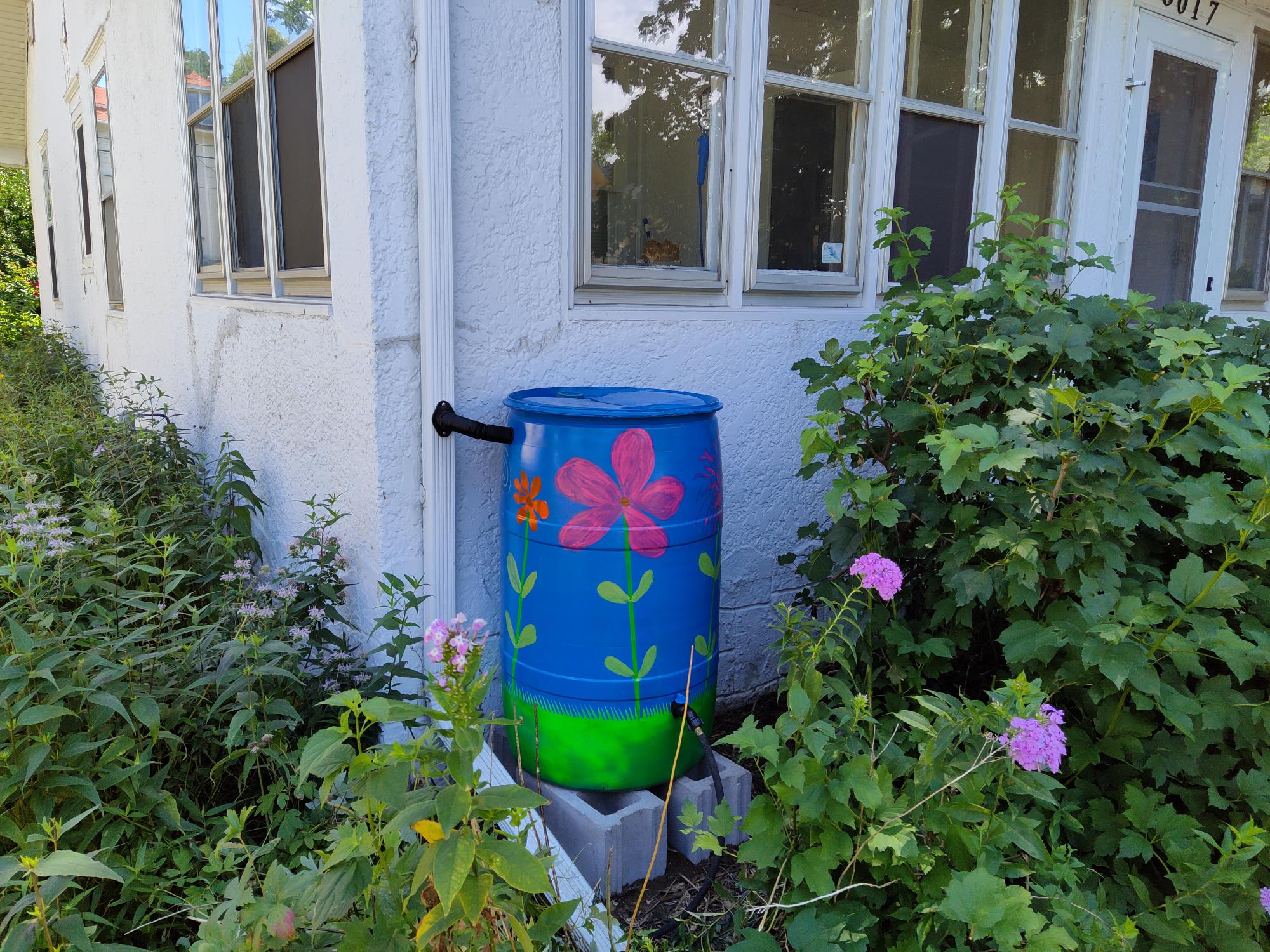Rain barrel attached to gutter, painted with flowers