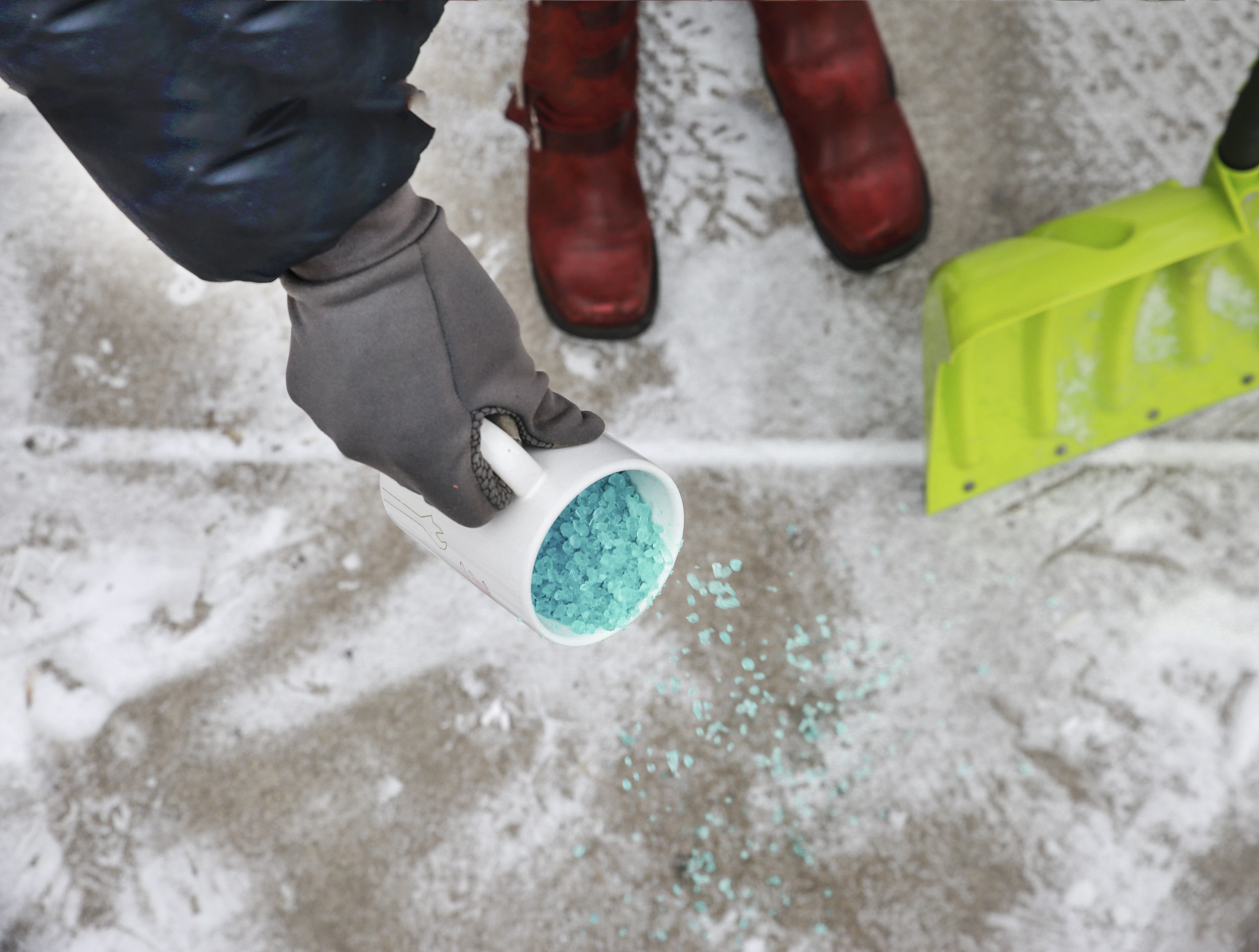 Person applies salt to snowy sidewalk 