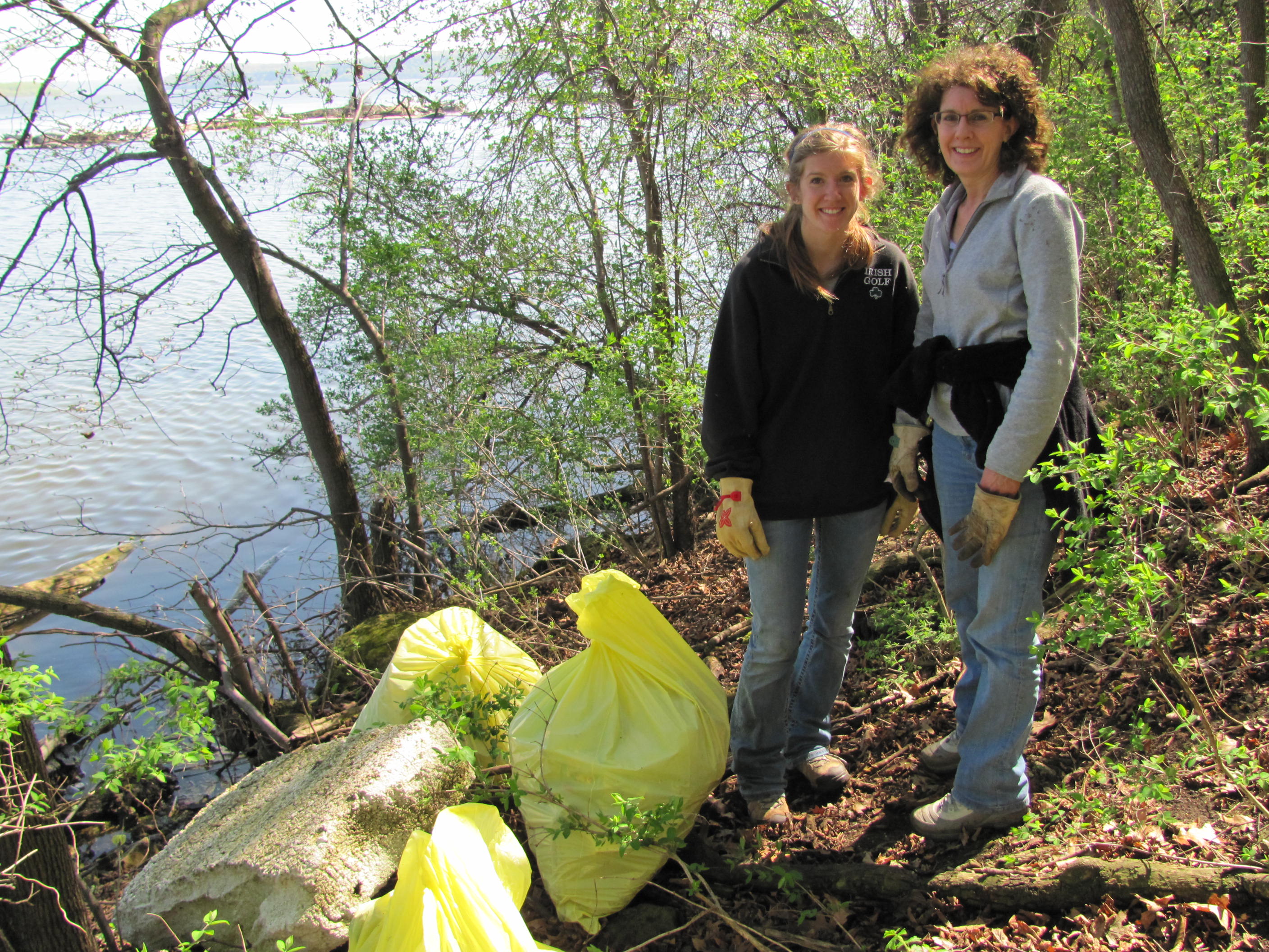 Two volunteers with trash bags by the river