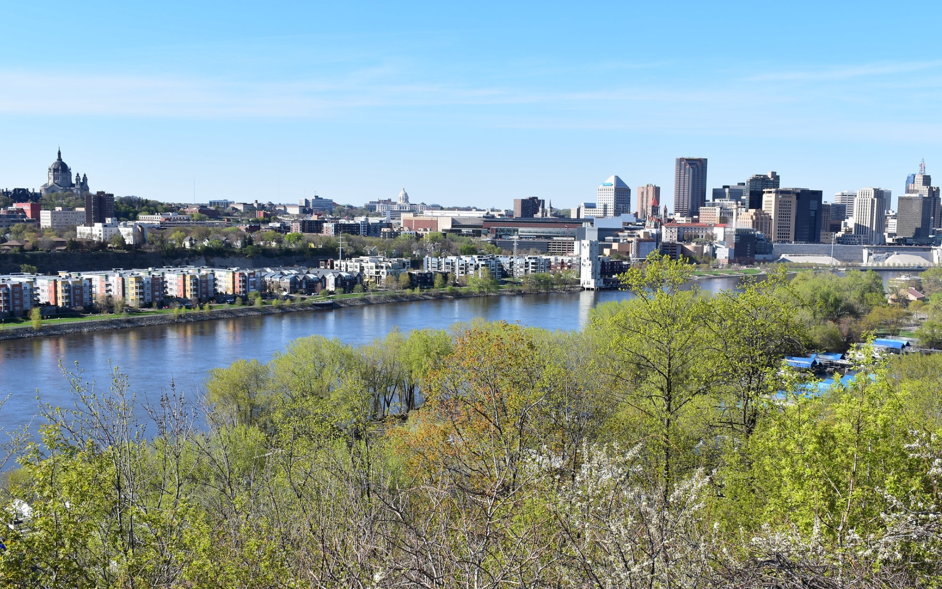 The downtown St. Paul skyline stretches across the top of the frame, with the river and residential housing in the foreground.