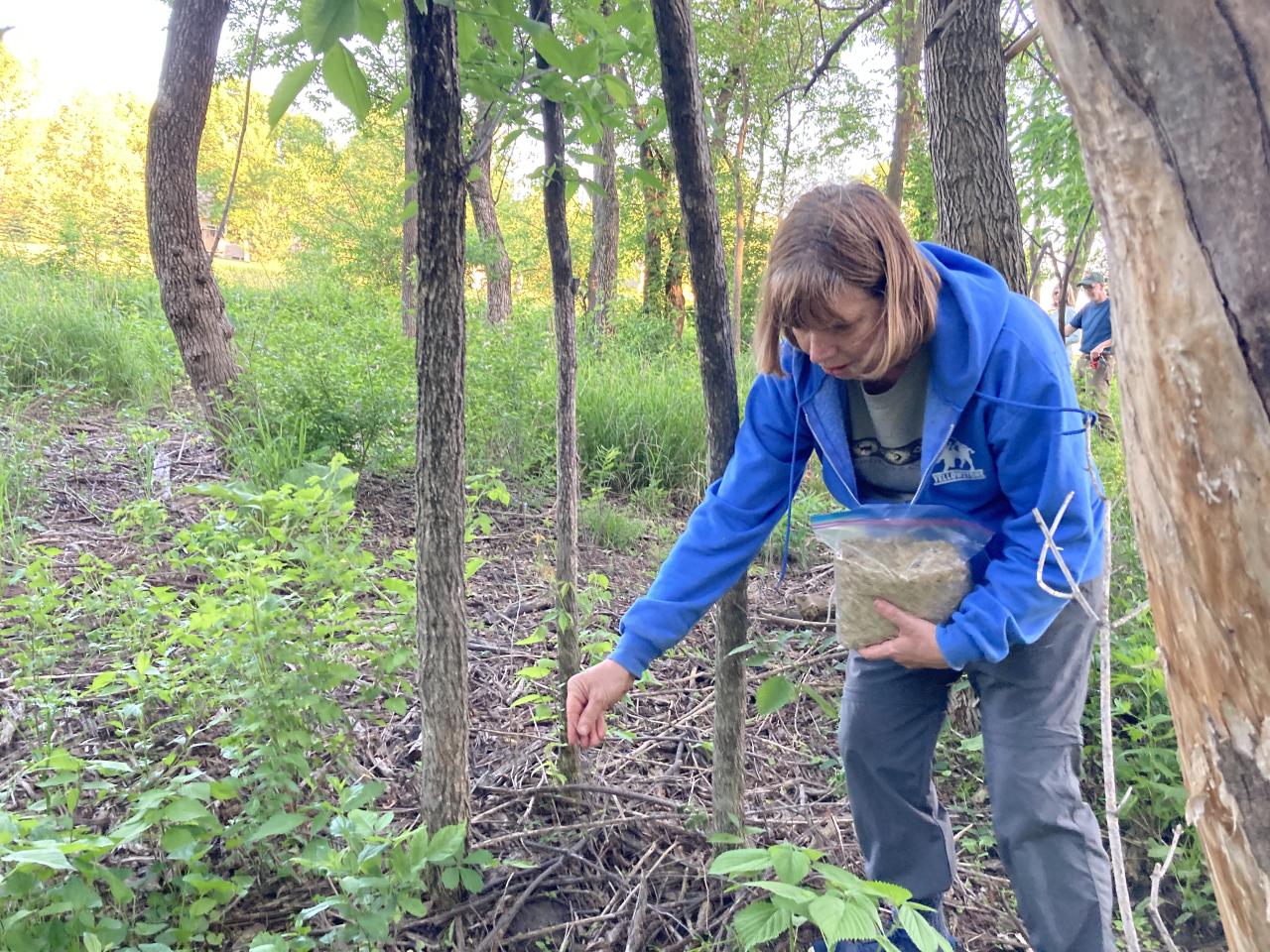 Volunteer Karla distributes grass seed at Vermillion River Linear Park