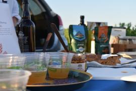 Plastic cups of Kernza beer on a table, with homemade snack bars just past them and bags of products that feature clean-water crops on the other end of the table. 