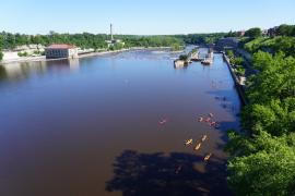A collection of kayakers, seen from far above, approaches Lock and Dam 1 on the Mississippi River during a June event.