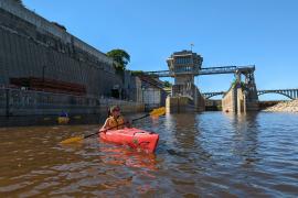 A kayaker paddles away from Lock and Dam 1 on a sunny June day in 2022.