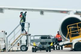 A worker refueling an airplane while standing beneath its wing.