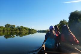 Three young people paddle a canoe on the river