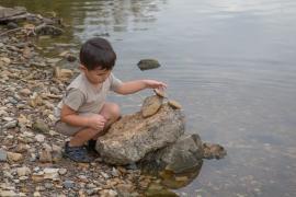 Young child is playing with rocks along the bank of the Mississippi River