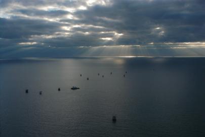 A wide view of a tugboat in the Gulf of Mexico, against a cloudy sky.