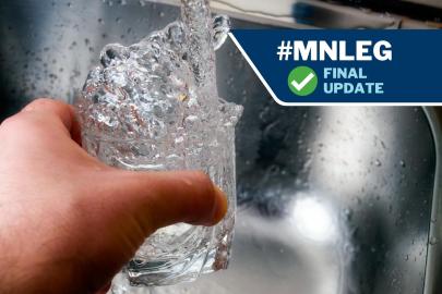 A hand holding a glass up to a running faucet. Water is filling the glass. 