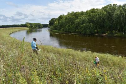 Two volunteers work in prairie by a river