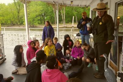Students gather around a ranger on a boat on the Mississippi River