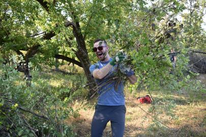 Volunteer in sunglasses smiles and hauls brush