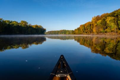 Tip of a canoe in the river by forested area