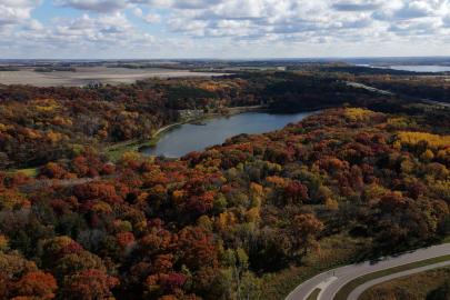 Aerial view of lake near river surrounded by fall forest