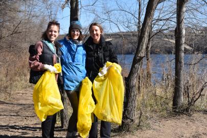 Three people with cleanup bags by the river