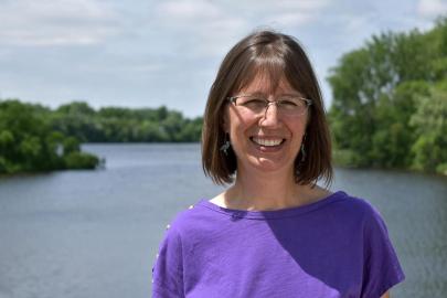 Karen Schik, smiling for the camera in front of the Mississippi River.