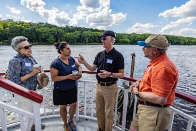 Four people talk on a boat on the river