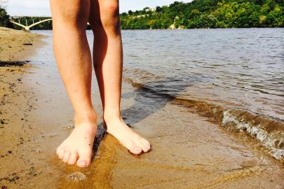Bare feet standing on the sand along the shores of the Mississippi River in the Twin Cities.