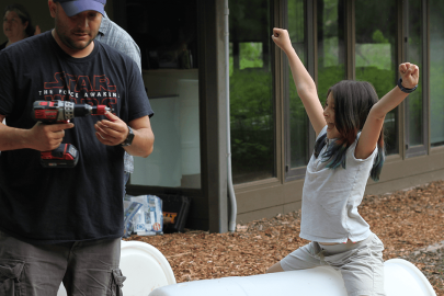 Two people putting together a rain barrel