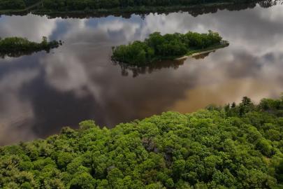 Aerial photo of forested riverbanks and river reflecting clouds