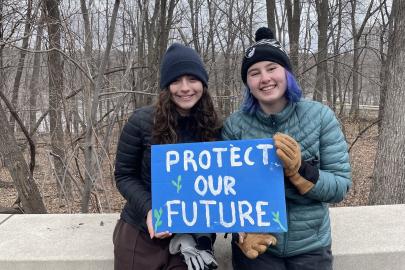 Two young people hold a sign in the river gorge that reads "Protect our future"