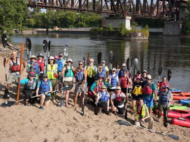 Kayaker volunteers with paddles on the river shore