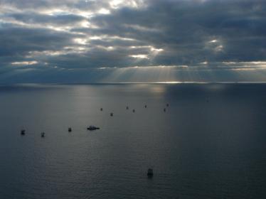 A wide view of a tugboat in the Gulf of Mexico, against a cloudy sky.