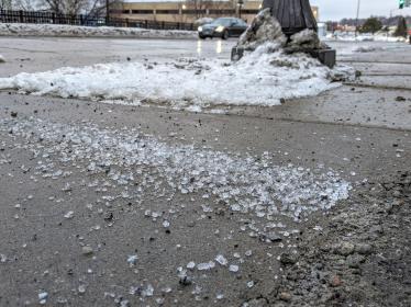A pile of deicing salt piled along a sidewalk in winter.