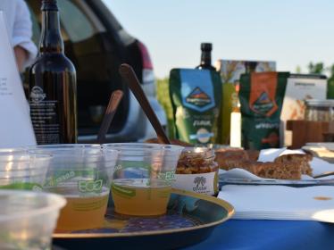 Plastic cups of Kernza beer on a table, with homemade snack bars just past them and bags of products that feature clean-water crops on the other end of the table. 