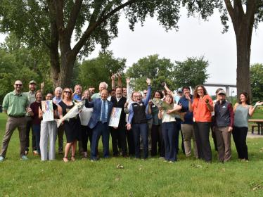 Coalition members, legislators and agency staff all pose for a celebratory photo outside at Harriet Island.