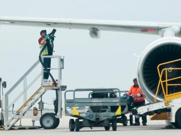 A worker refueling an airplane while standing beneath its wing.