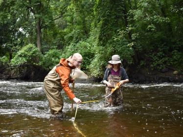 Two SHEP volunteers wade in stream