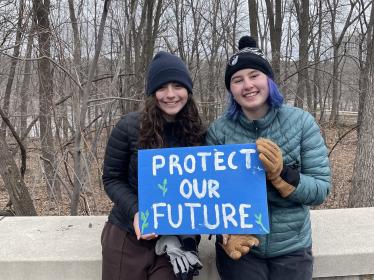 Two young people hold a sign in the river gorge that reads "Protect our future"