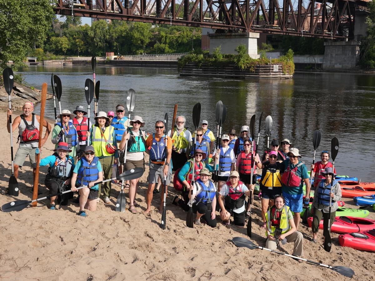 Kayaker volunteers with paddles on the river shore