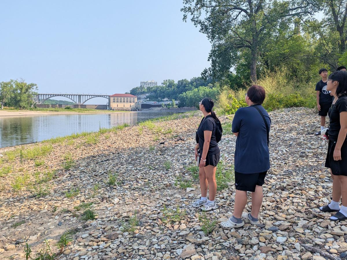 ESI summer program participants stand on the banks of the river looking at the Ford dam