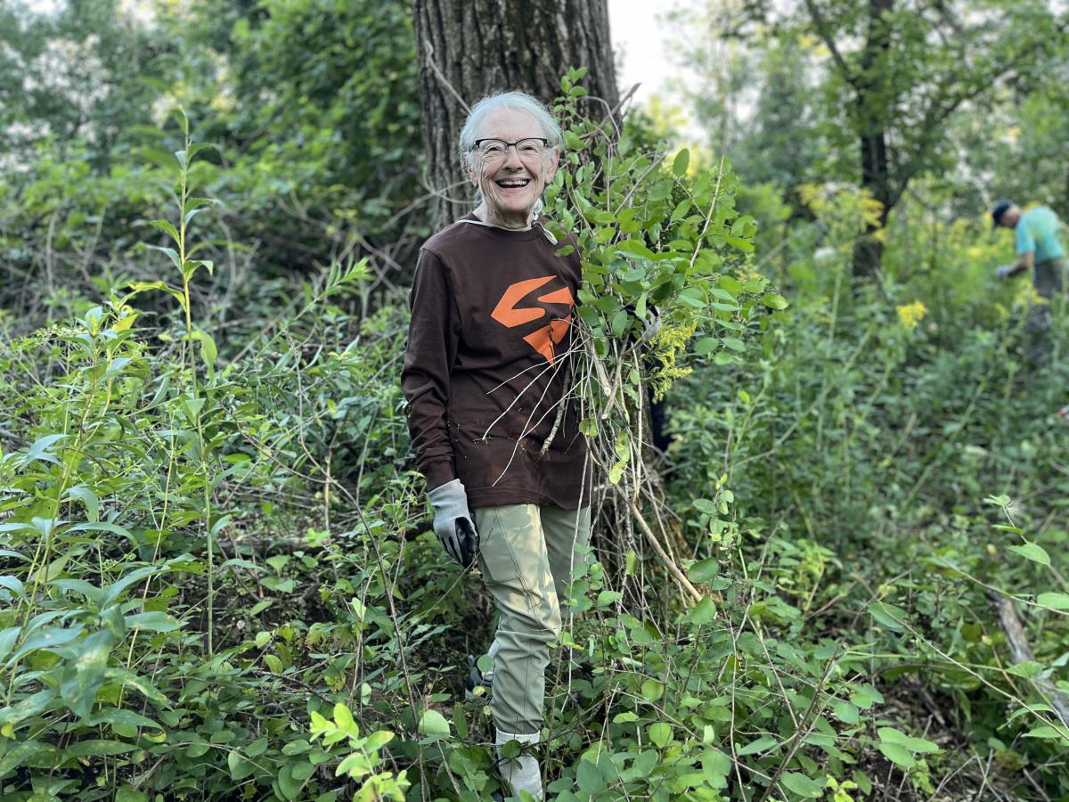 Mary Kay holding invasive plants she's pulled in the forest