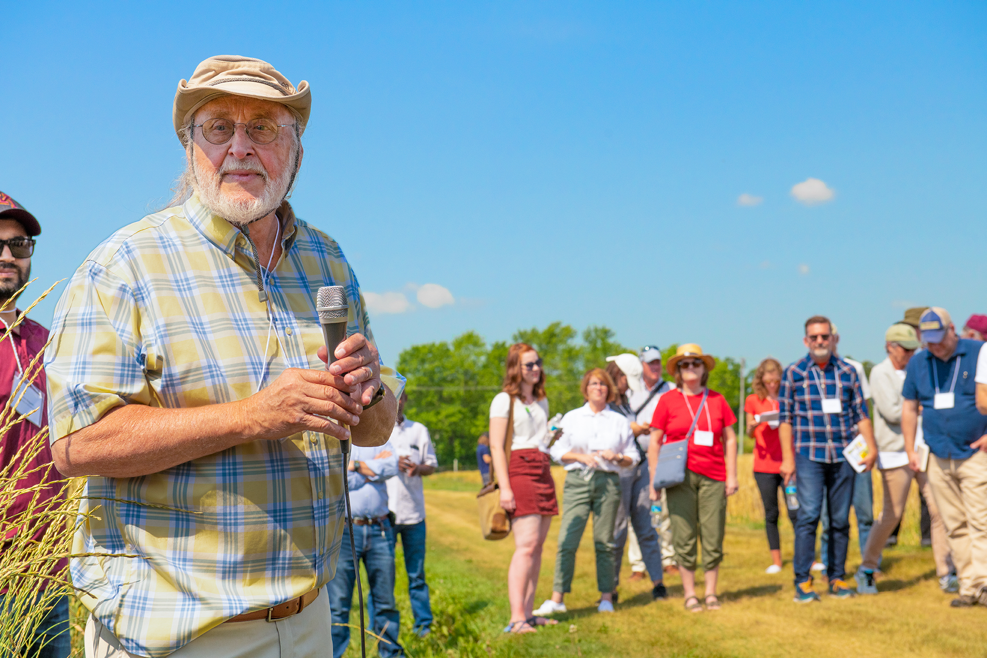 Dr. Don Wyse speaks to policymakers near an ag field.